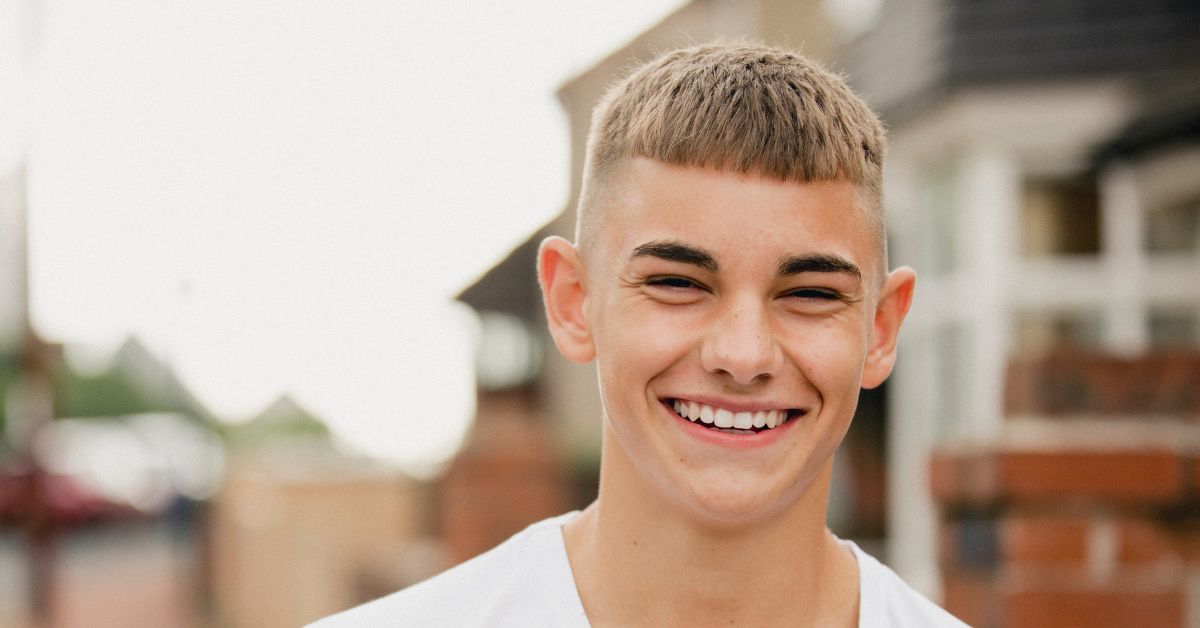 A teenage boy smiles while walking outdoors.