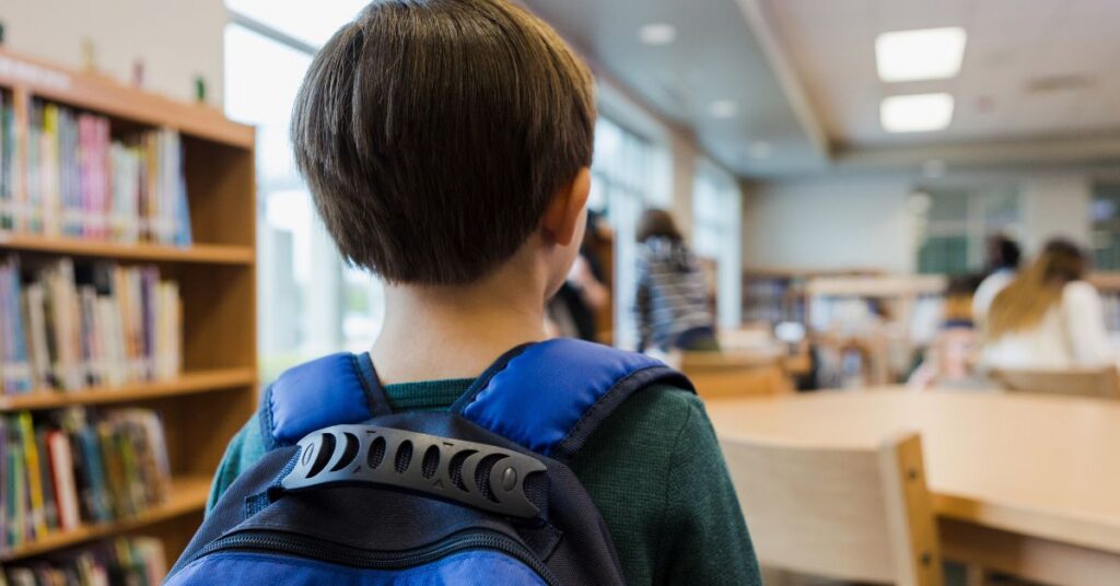 A young boy walks into a classroom.