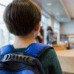 A young boy walks into a classroom.