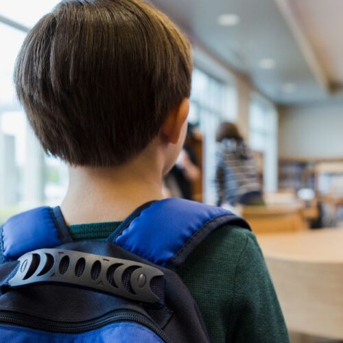 A young boy walks into a classroom.