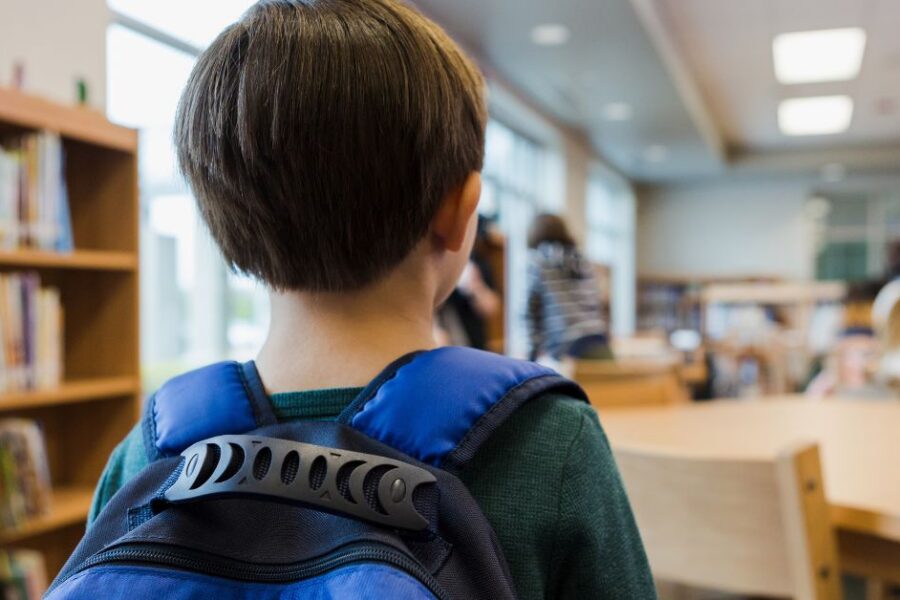 A young boy walks into a classroom.