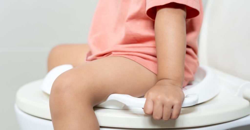 A close up of a constipated child sitting on a toilet seat.