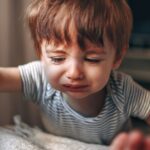 A crying young child climbs into bed with his parents.