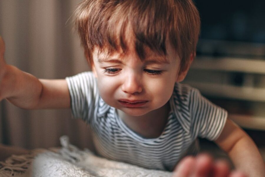 A crying young child climbs into bed with his parents.