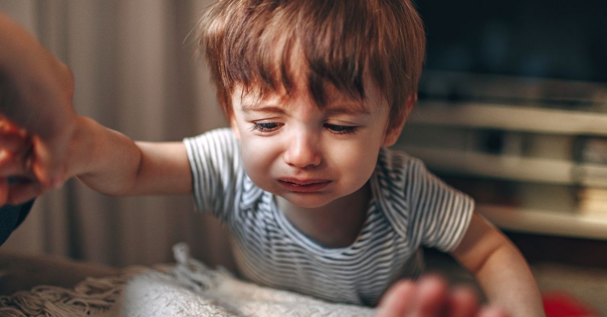 A crying young child climbs into bed with his parents.