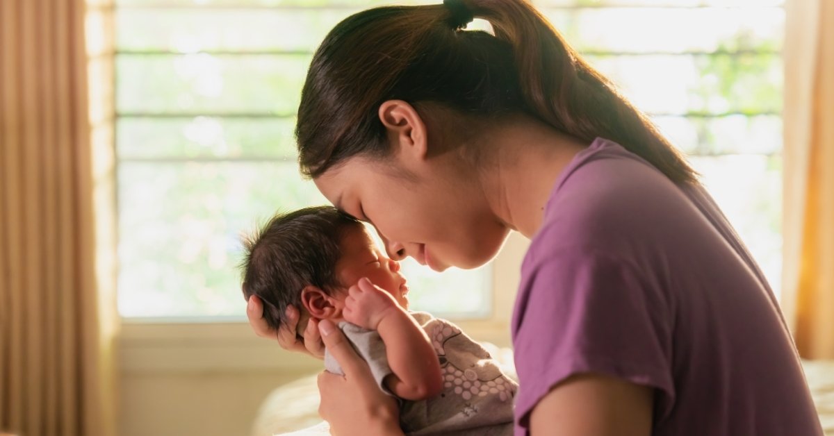 A postpartum mom snuggles her newborn.