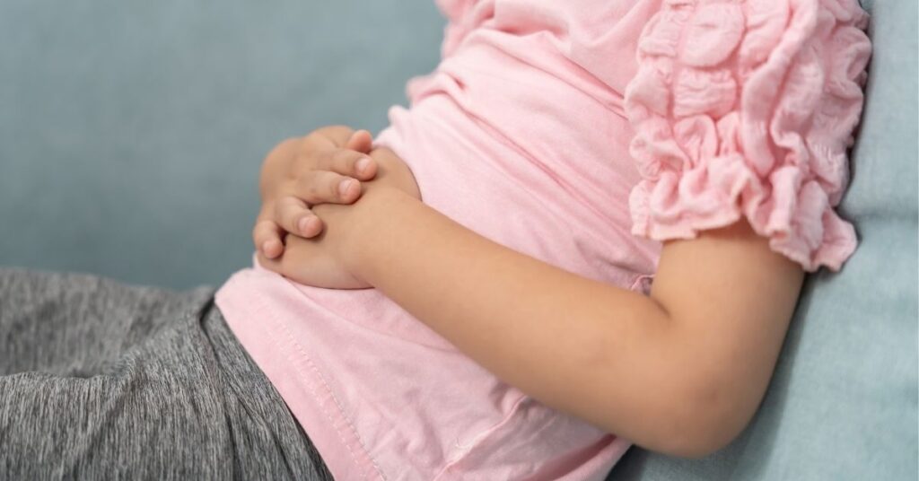 A close up of a young girl holding her stomach.