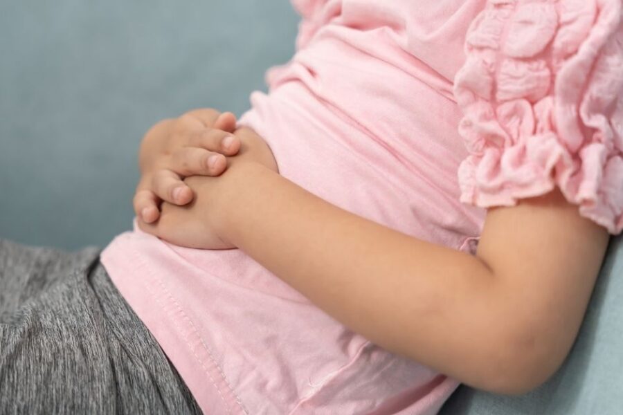 A close up of a young girl holding her stomach.